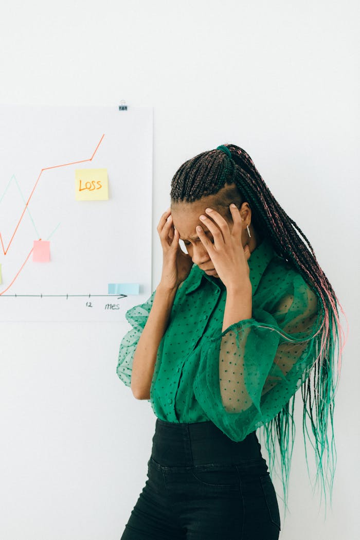 Businesswoman in distress over financial graph showing loss indoors.